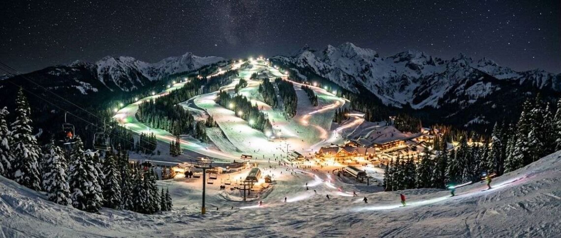 Stevens Pass ski resort at night with illuminated slopes under floodlights and starry sky above Cascade Mountains