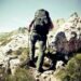 how to use trekking poles for hiking — hiker planting both poles mid-stride on a rocky trail