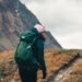 What to wear when hiking: hiker in beanie, shell jacket, leggings, wool socks and boots on a mountain trail