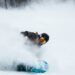 Snowboarder carving deep powder with a hand near the snow, the exact fall pattern wrist guards snowboarding riders wear them for