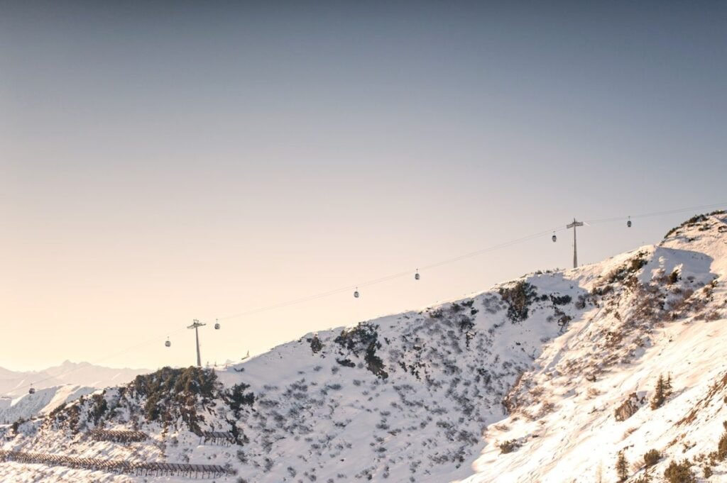 Gondola cables crossing a snowy mountain ridge under a clear sky ahead of the 2026-2027 winter weather predictions season
