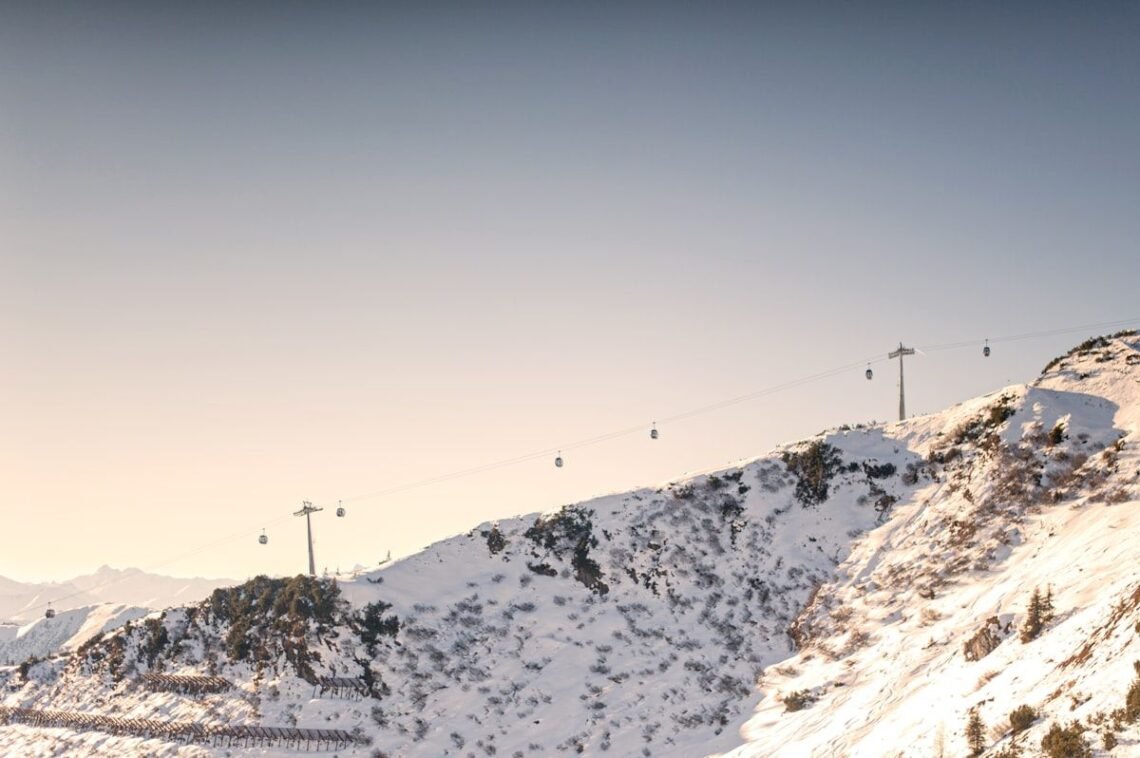 Gondola cables crossing a snowy mountain ridge under a clear sky ahead of the 2026-2027 winter weather predictions season