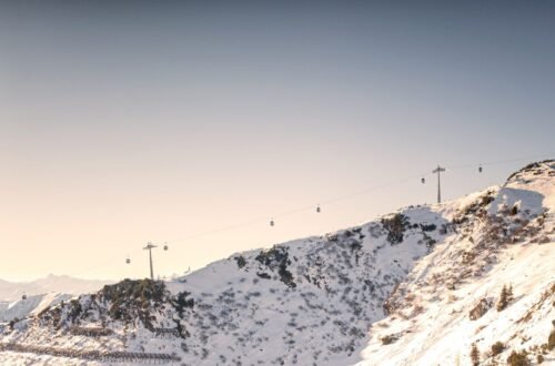 Gondola cables crossing a snowy mountain ridge under a clear sky ahead of the 2026-2027 winter weather predictions season