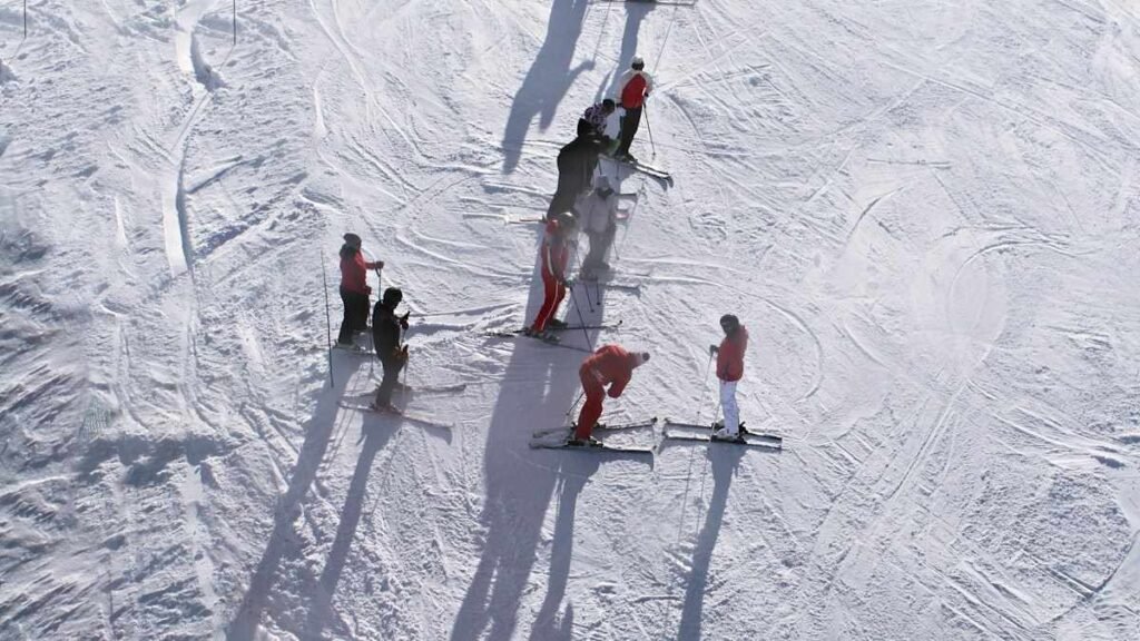 Beginner ski lesson group on a gentle slope deciding skiing vs snowboarding which is easier to learn
